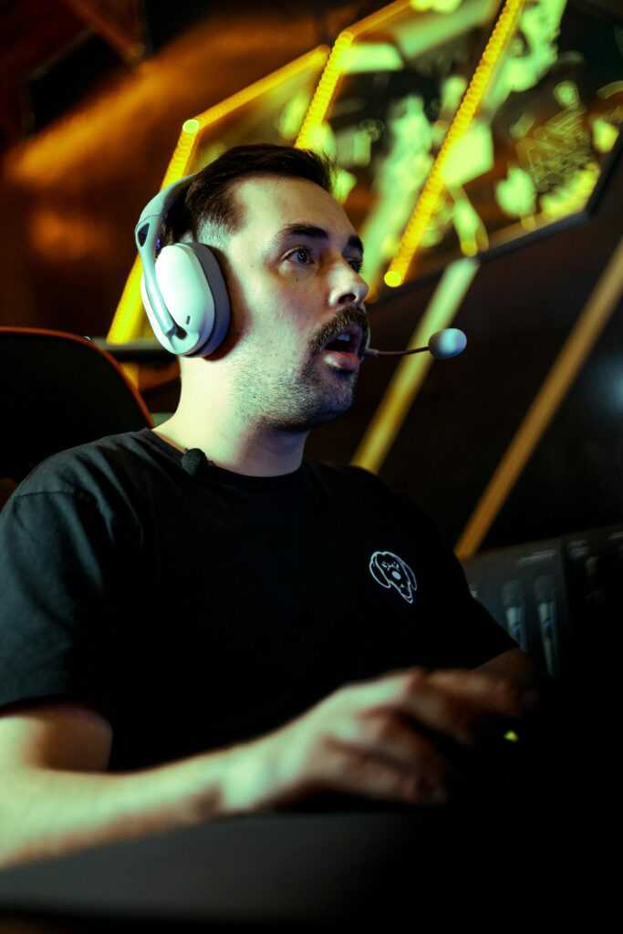 A gamer intensely engaged in an esports competition, wearing a headset in a dimly lit room.