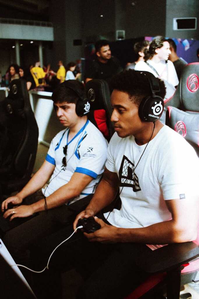 Two gamers intensely focused during a competitive esports event, wearing headsets and using controllers.