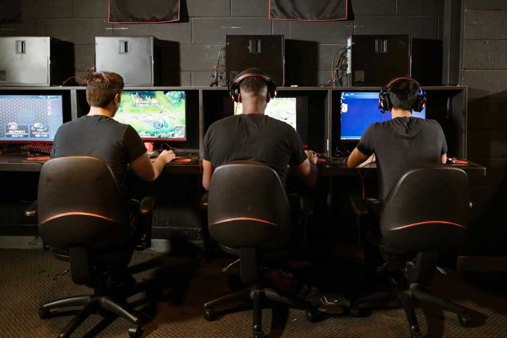 A group of men intensely focused on playing video games at a modern gaming arcade.