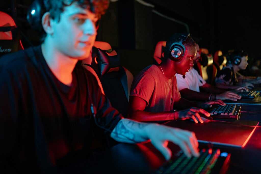 Young gamers competing in a gaming tournament, using headsets and keyboards with focused expressions.